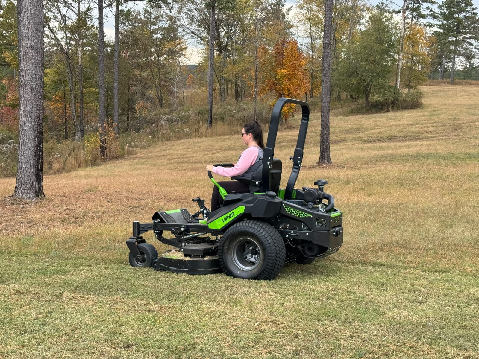 An operator mowing a lawn in an autumn field
