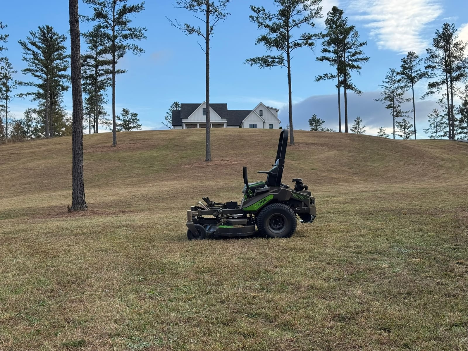 Distant mower with farmhouse on hill, wide scenic
